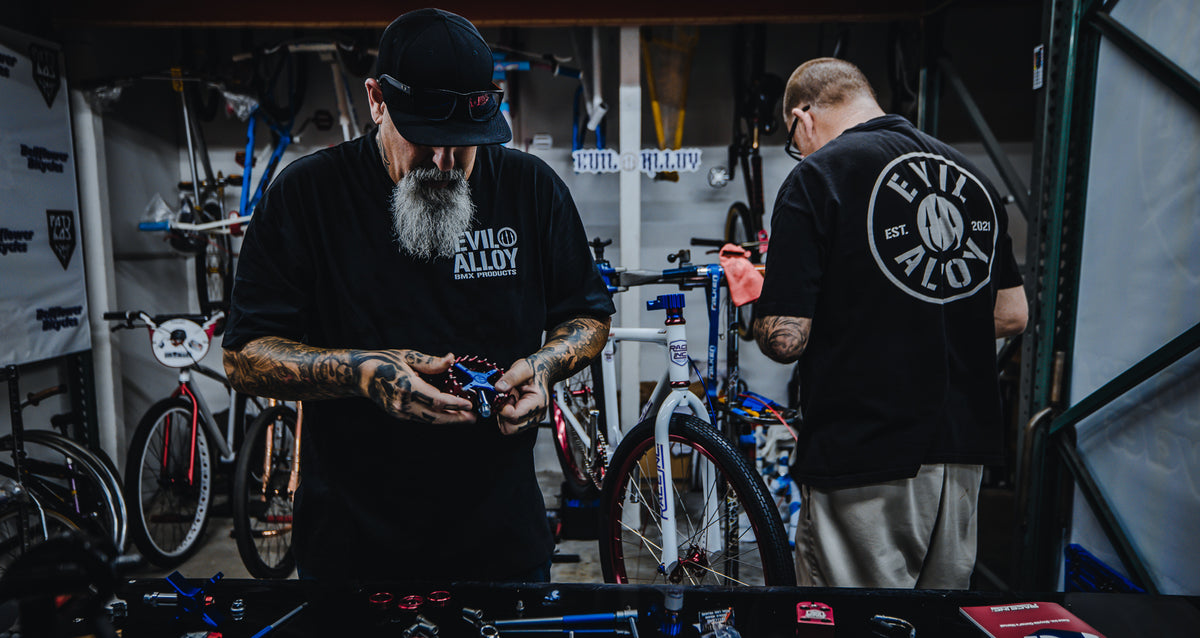 Two people working on a custom bike in the Evil Alloy workshop